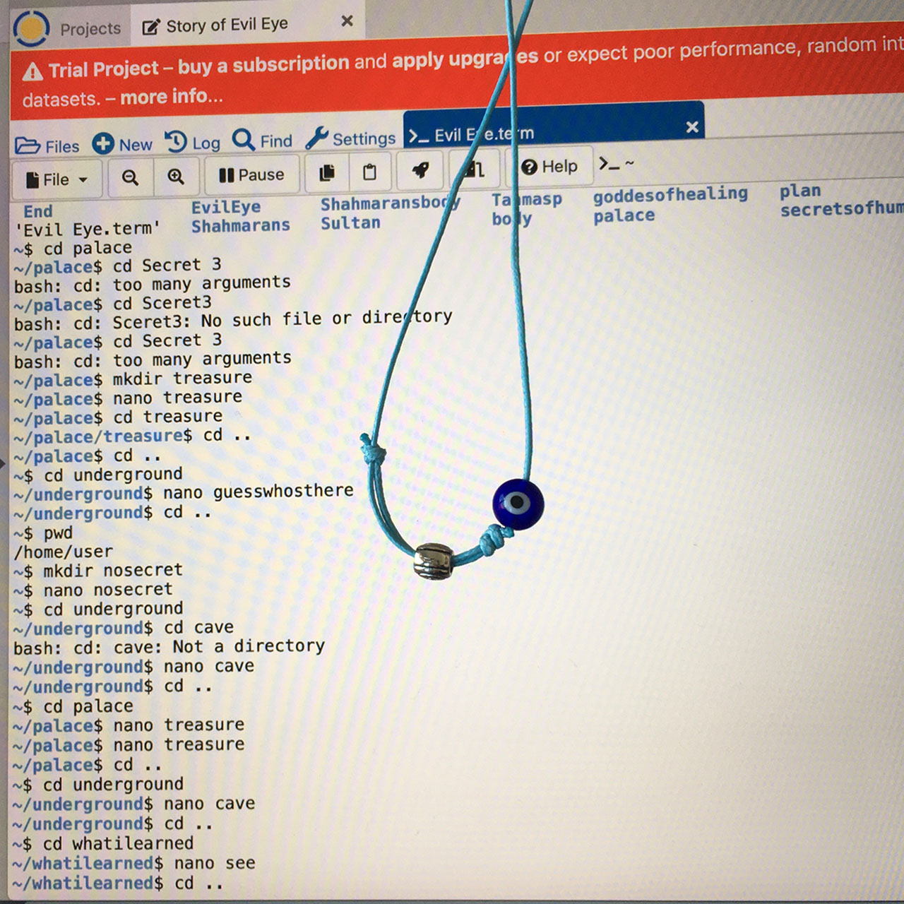 In front of a computer screen, an evil eye bracelet is hanging on a blue string. The screen shows some moire interference, and there is a tab open that is called 'Story of Evil Eye' and that contains bash commands.